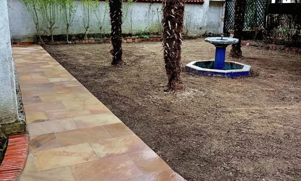 Allée en dalles de grès Madère bordée de gazon naturel devant une maison