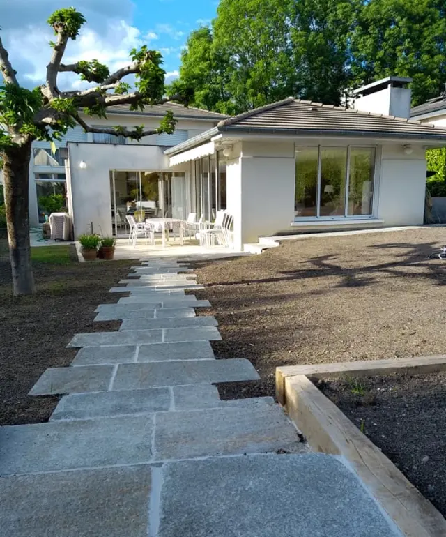 Allée en gravier de luzerne avec traverses en chêne menant à une maison