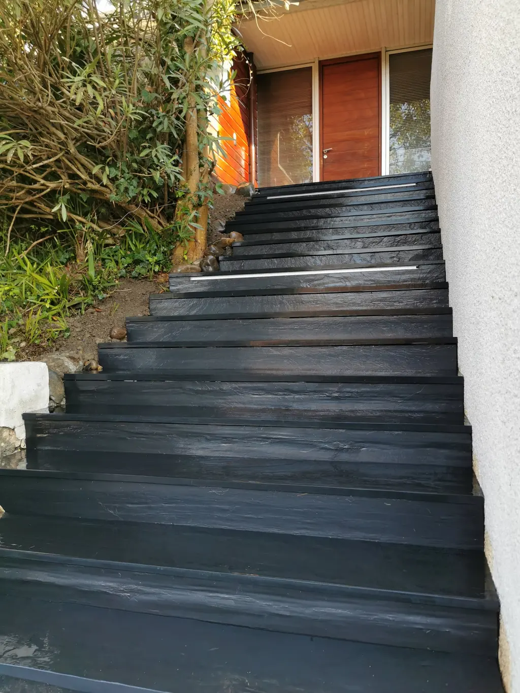 Escalier extérieur en schiste noir bordé de végétation