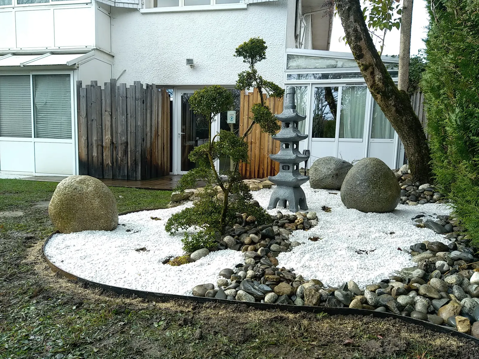 Massif d’inspiration japonaise avec niwaki, lanterne, galets et bordure corten