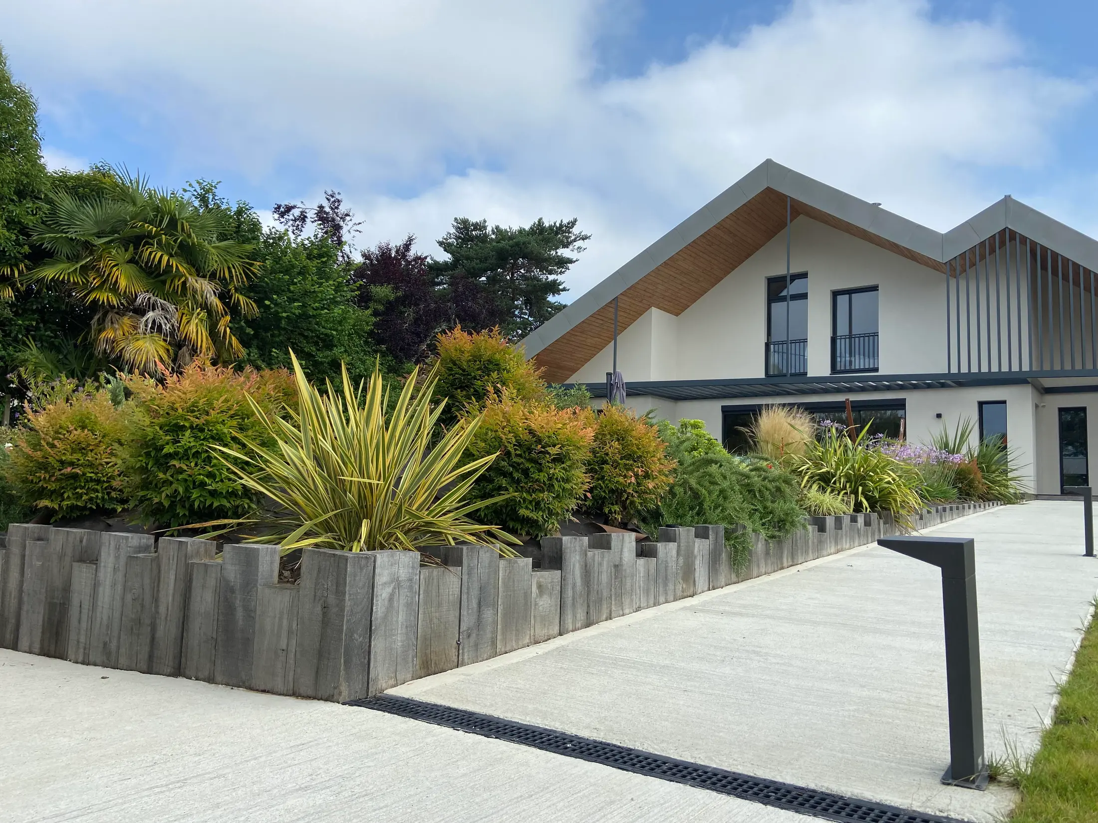 Mur de soutènement et clôture bois devant une maison contemporaine, photo Aux Jardins d’Elisa