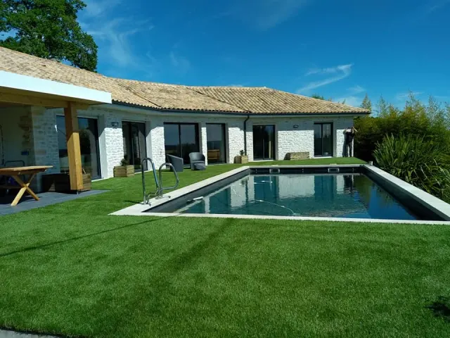 Plage de piscine en gazon synthétique devant une maison